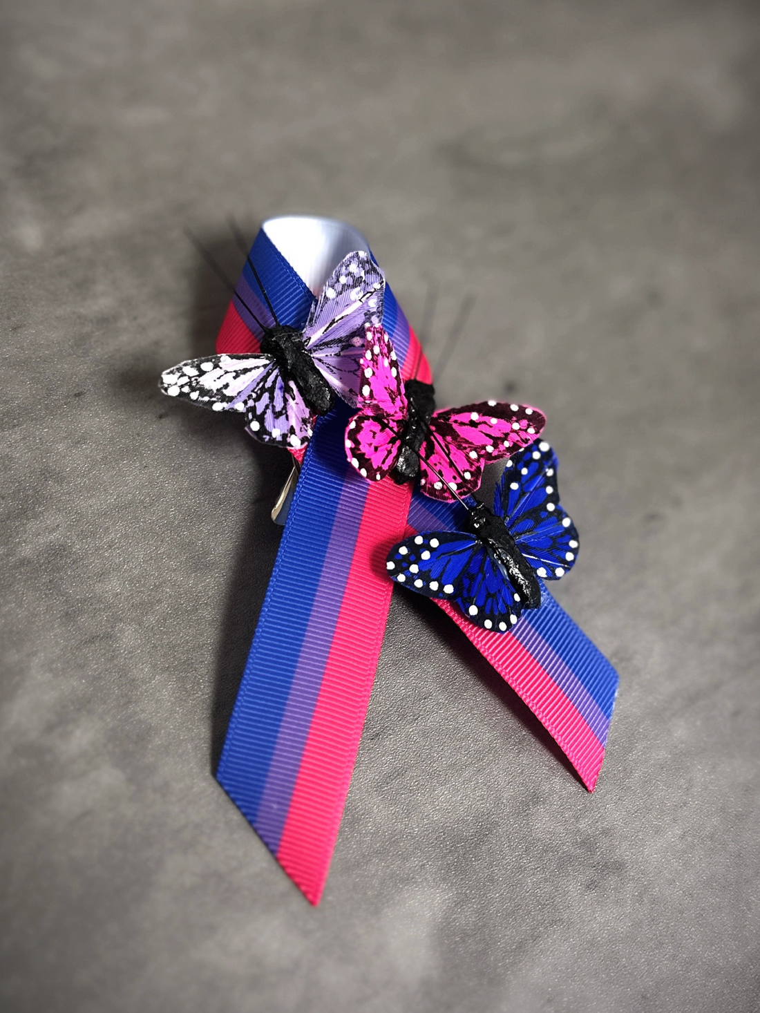 LGBTQ+ bi flag awareness pin featuring three colorful butterflies and vibrant ribbon design