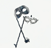 Black phantom-style men’s masquerade mask on stick with matching women’s rhinestone filigree mask, designed for elegant couple’s wear.