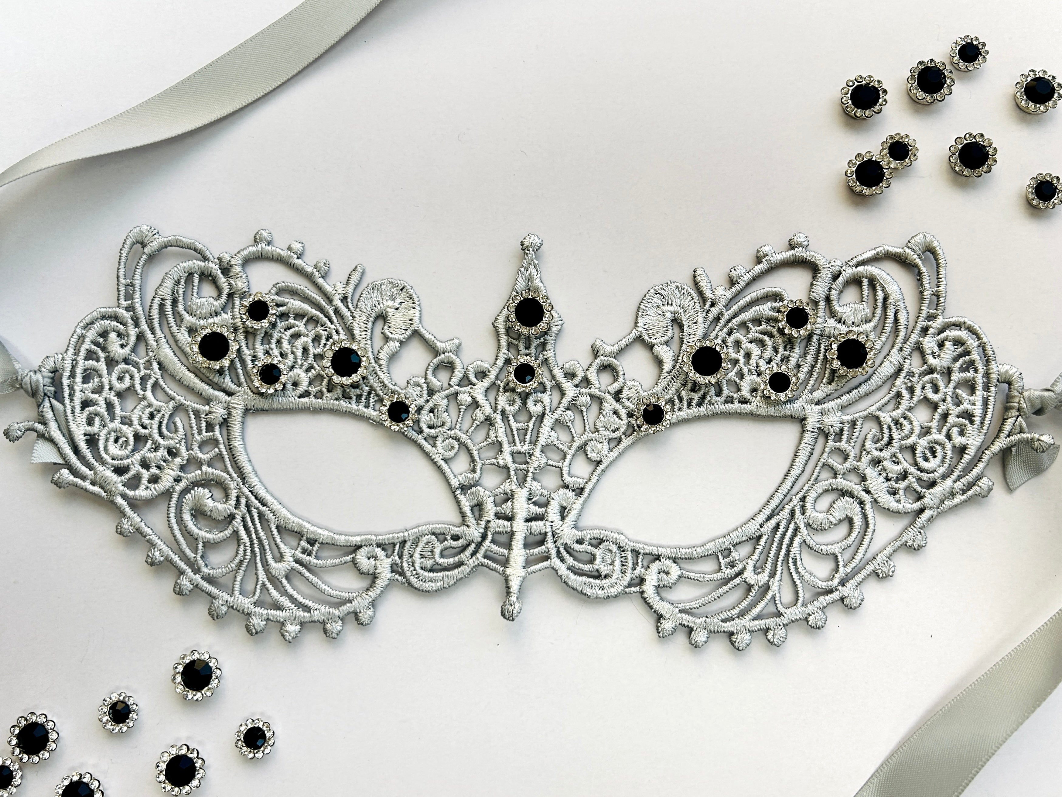 Silver lace masquerade mask with black crystal rhinestones for gala parties and Venetian formal events.
