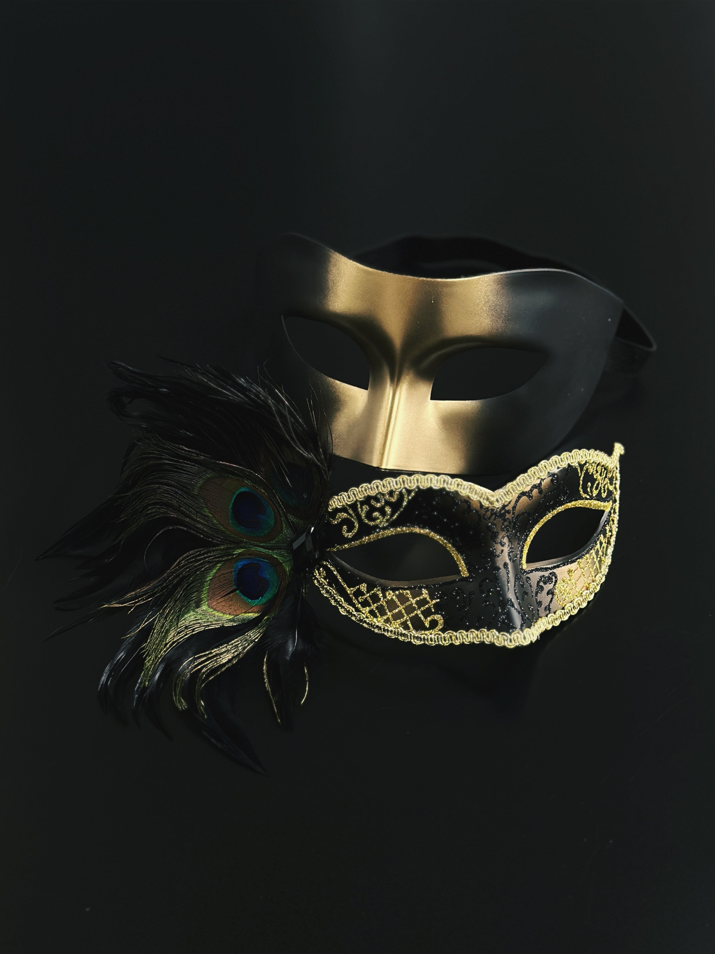 Black and gold couples masquerade masks, one with peacock feathers and glitter detailing, perfect for masquerade balls, prom, or Venetian parties.
