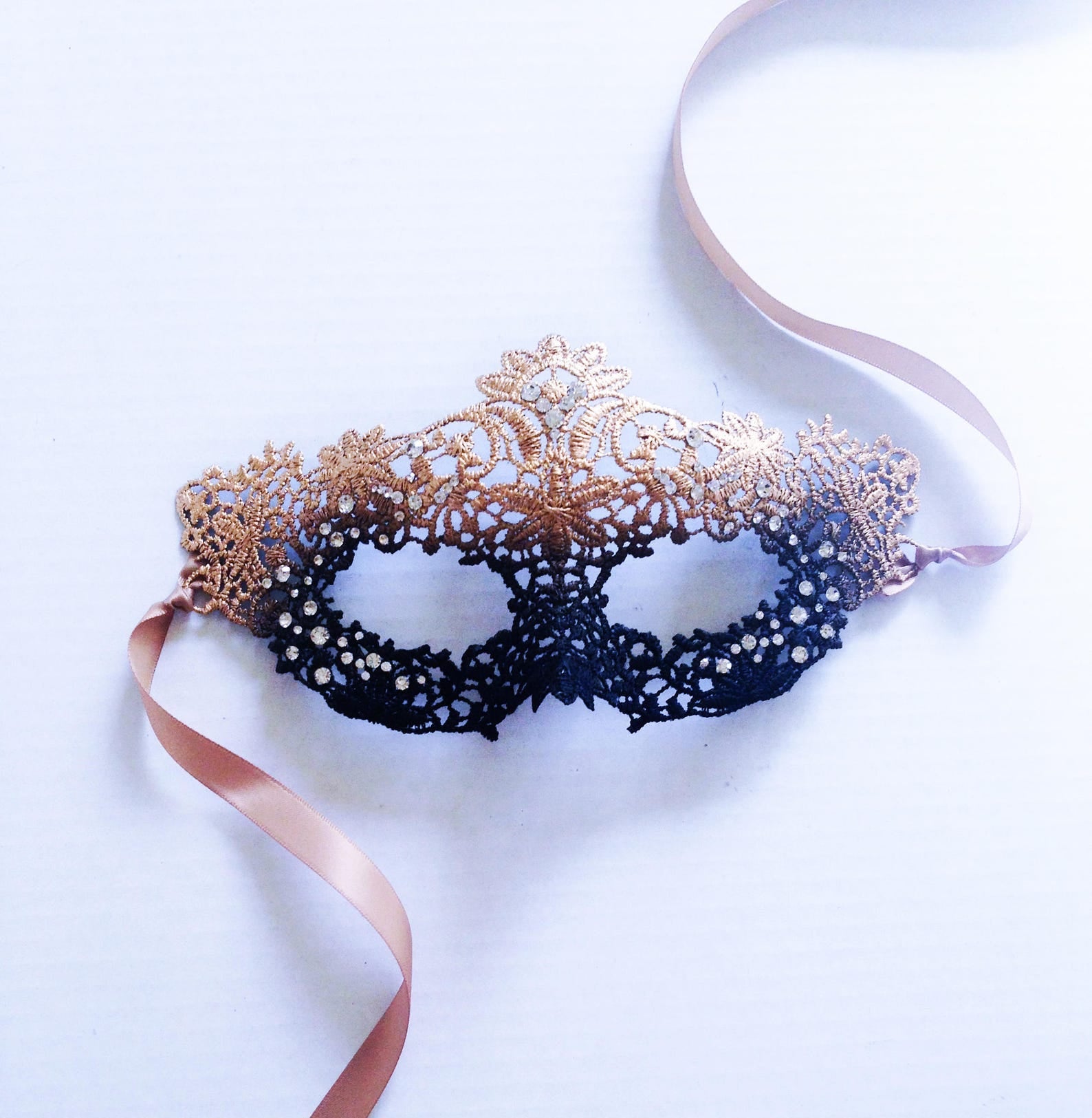 Elegant black and gold masquerade mask with filigree lace and ribbon ties