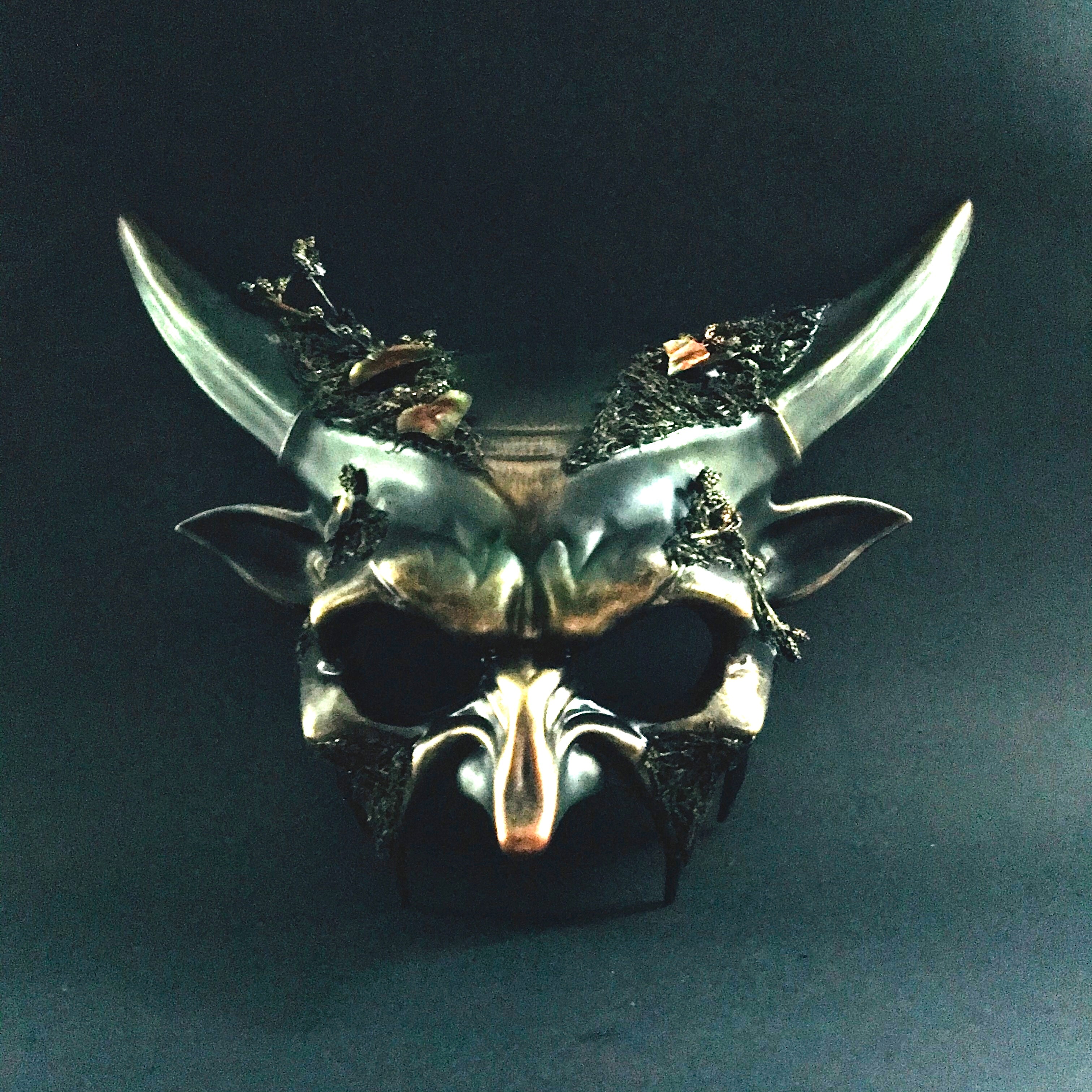 Black fantasy horn masquerade mask with moss and twisted vine embellishments