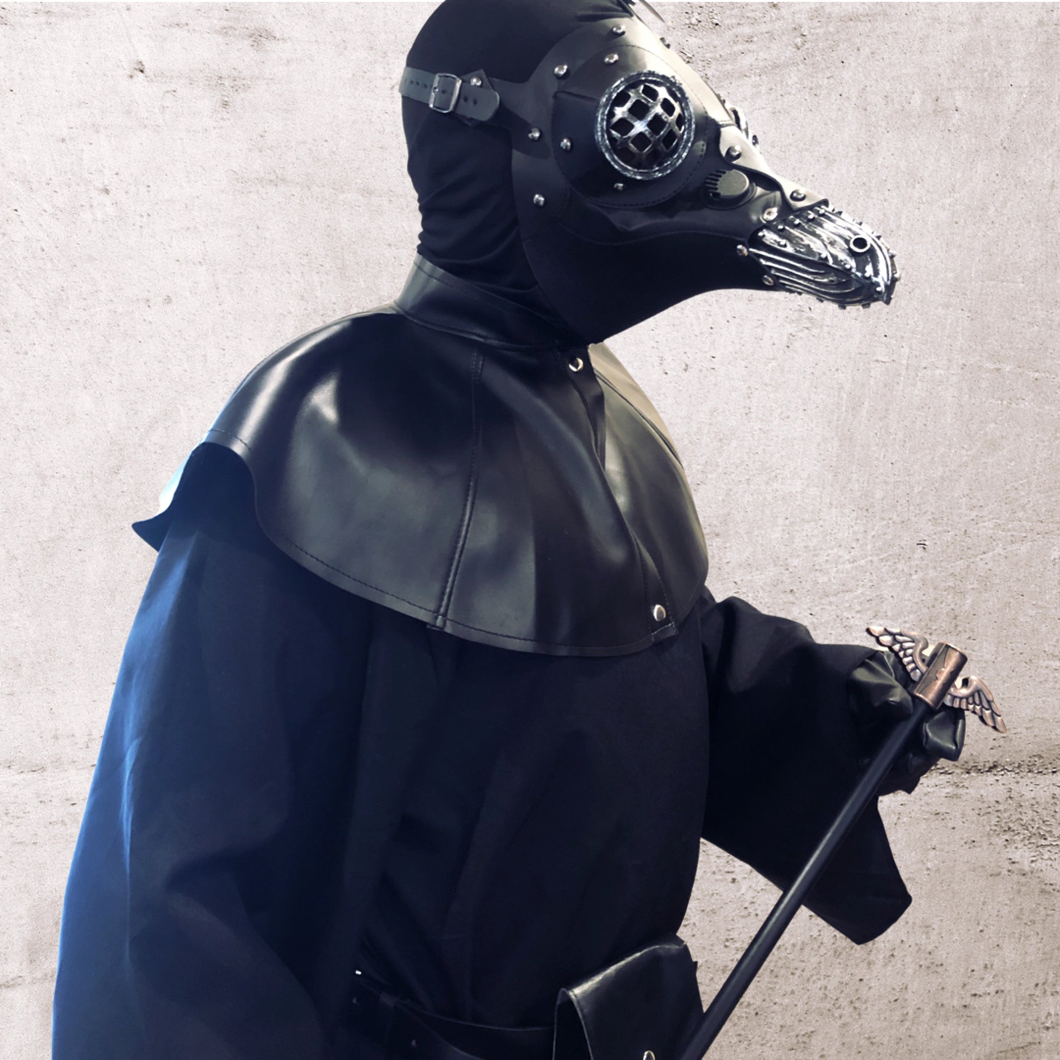 Man in gothic black leather plague doctor mask and robe with walking stick