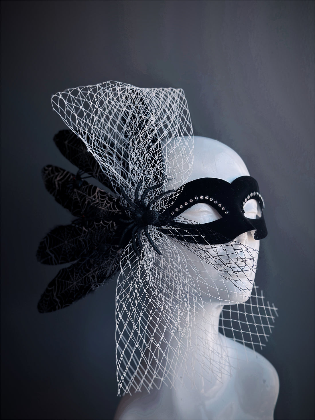 Black masquerade mask with spider, feather web detail, rhinestones, and white mesh veil for Halloween