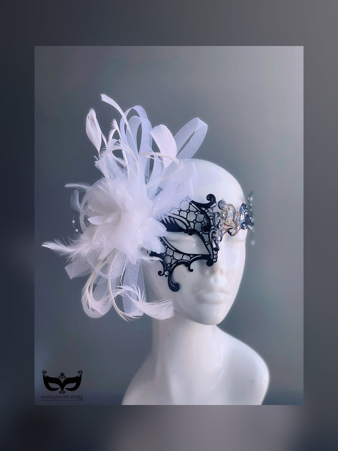 Black filigree masquerade mask with white feathers, tulle, and rhinestones for weddings and masquerade balls.