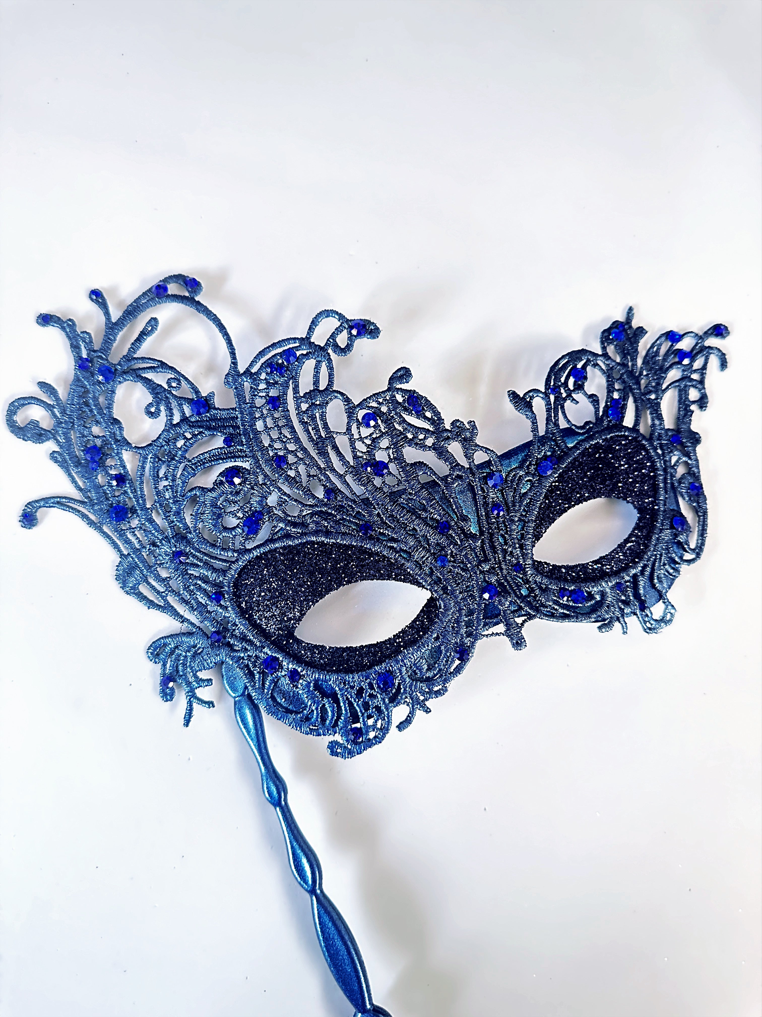 Blue lace masquerade mask with rhinestones and stick handle for masquerade ball or prom.