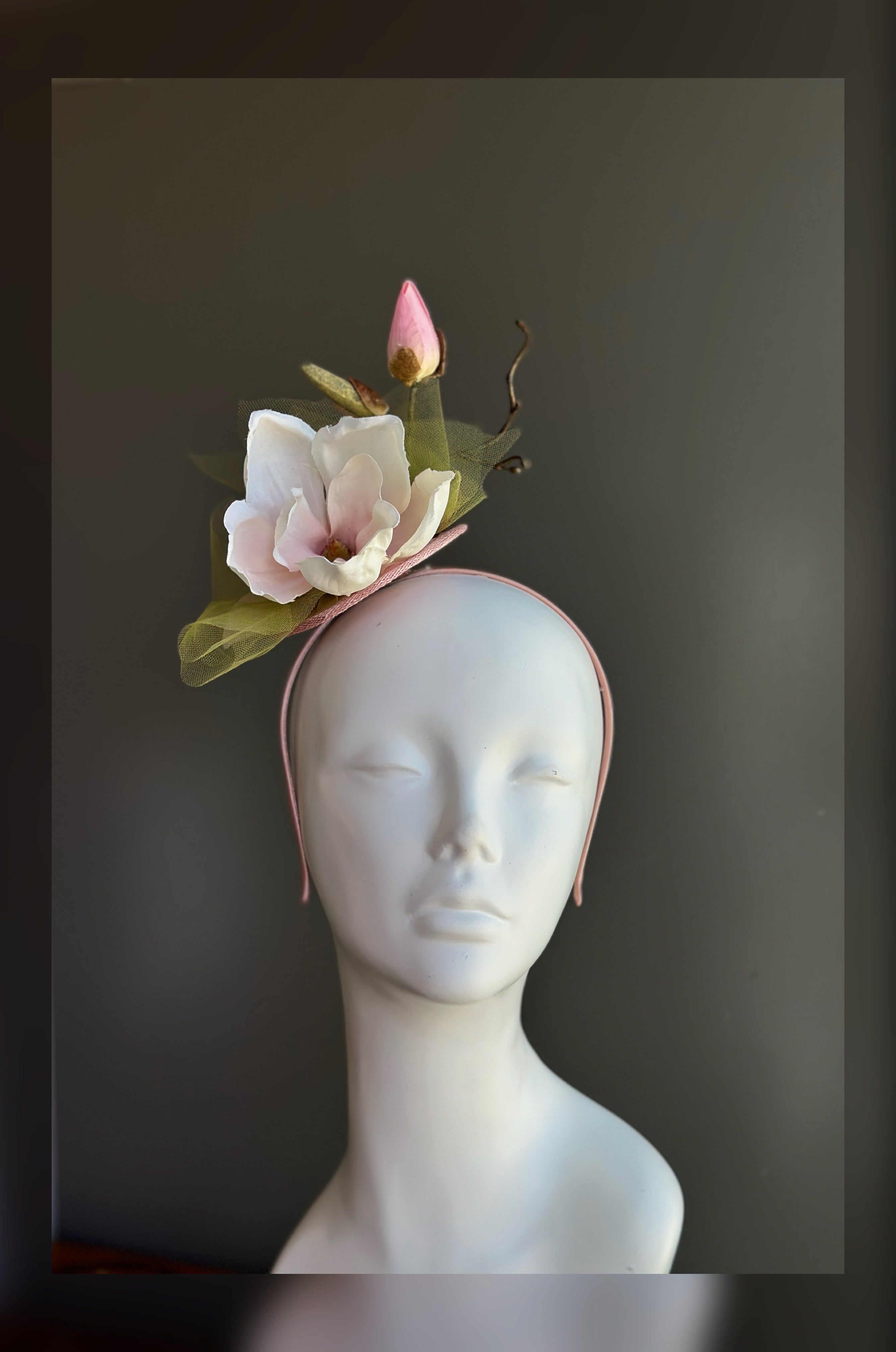 Blush pink magnolia fascinator hat with soft petals for weddings and garden party occasions.