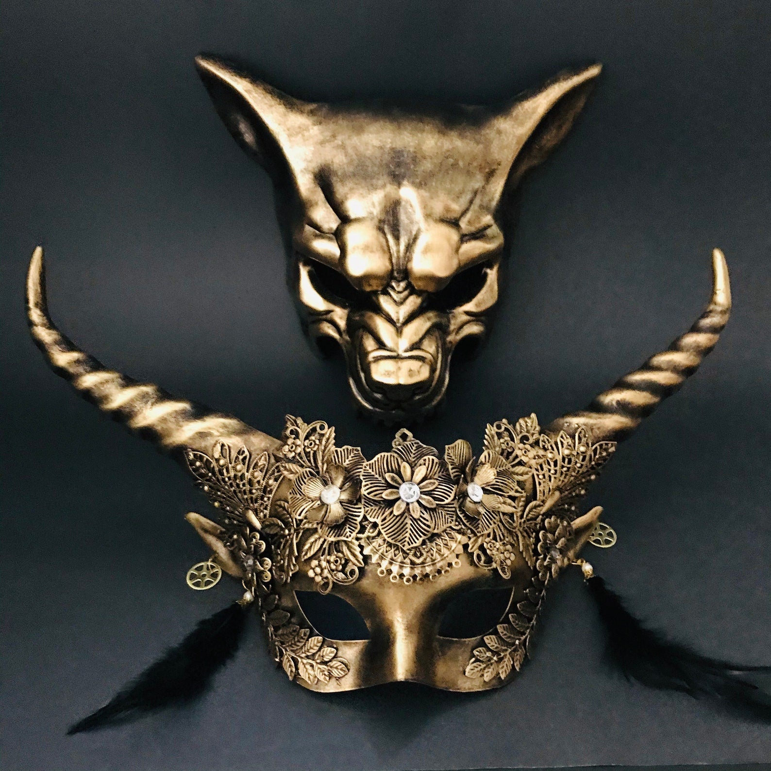 Gold horn masquerade mask set for couples featuring a floral horned women’s mask and a demon-style men’s mask.