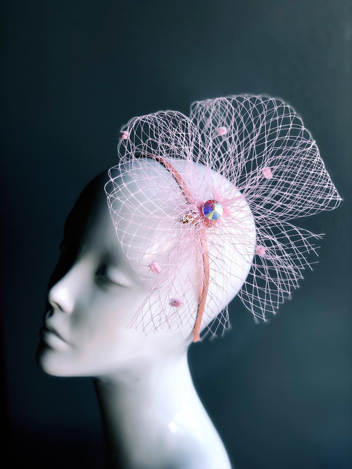 A pink net bow, gathered with a gemstone and attached on a matching headband