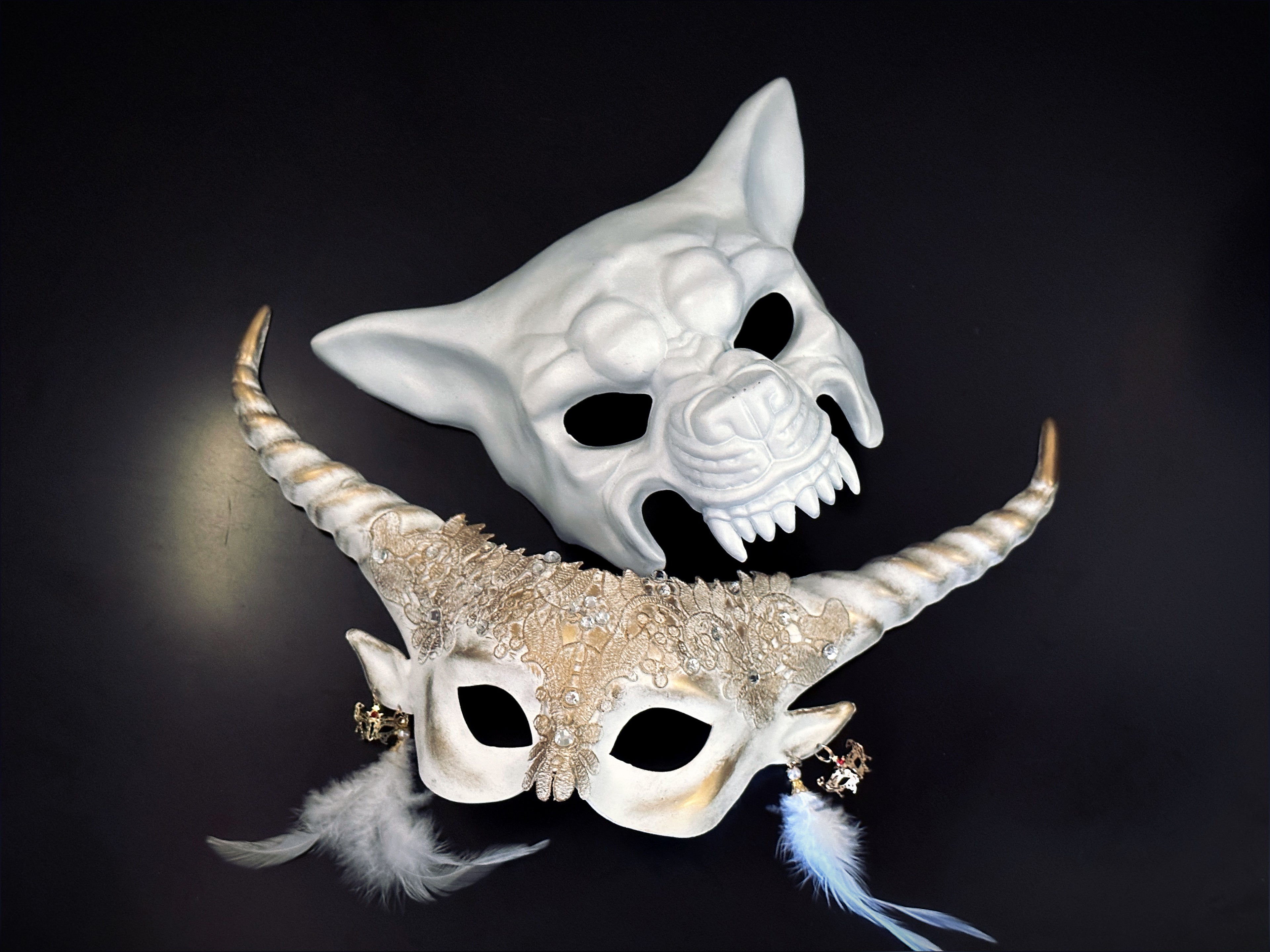 Silver-gray fantasy elf horn masquerade mask with floral filigree, gear charms, and black feather details