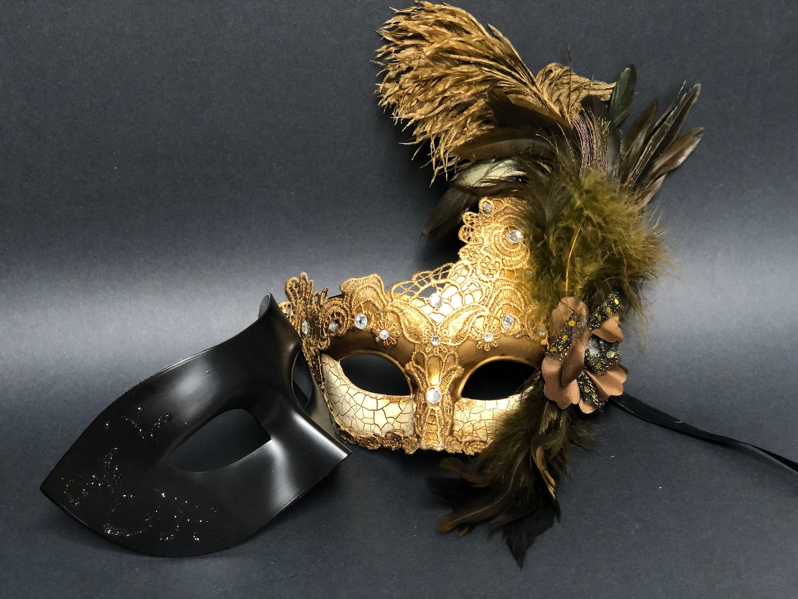 Elegant black couples masquerade mask set with feathered women’s mask and men’s classic mask, available in gold.