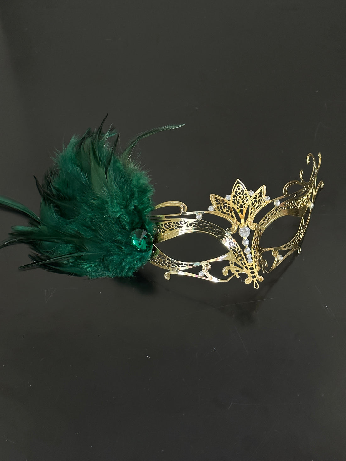 Ornate gold filigree party mask with bold green feather embellishment