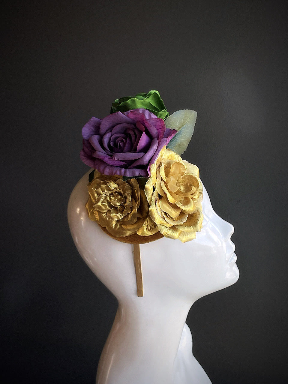 Elegant fascinator headband with gold and purple roses and green foliage for Mardi Gras or floral masquerade styling.