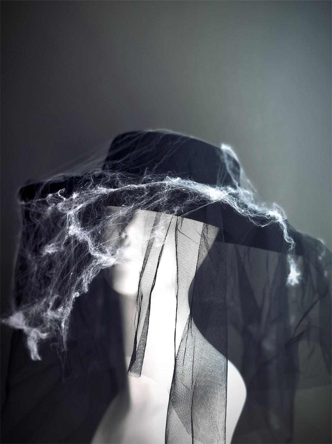 Halloween witch hat in black with mesh veil and cobweb accents, spooky gothic accessory.