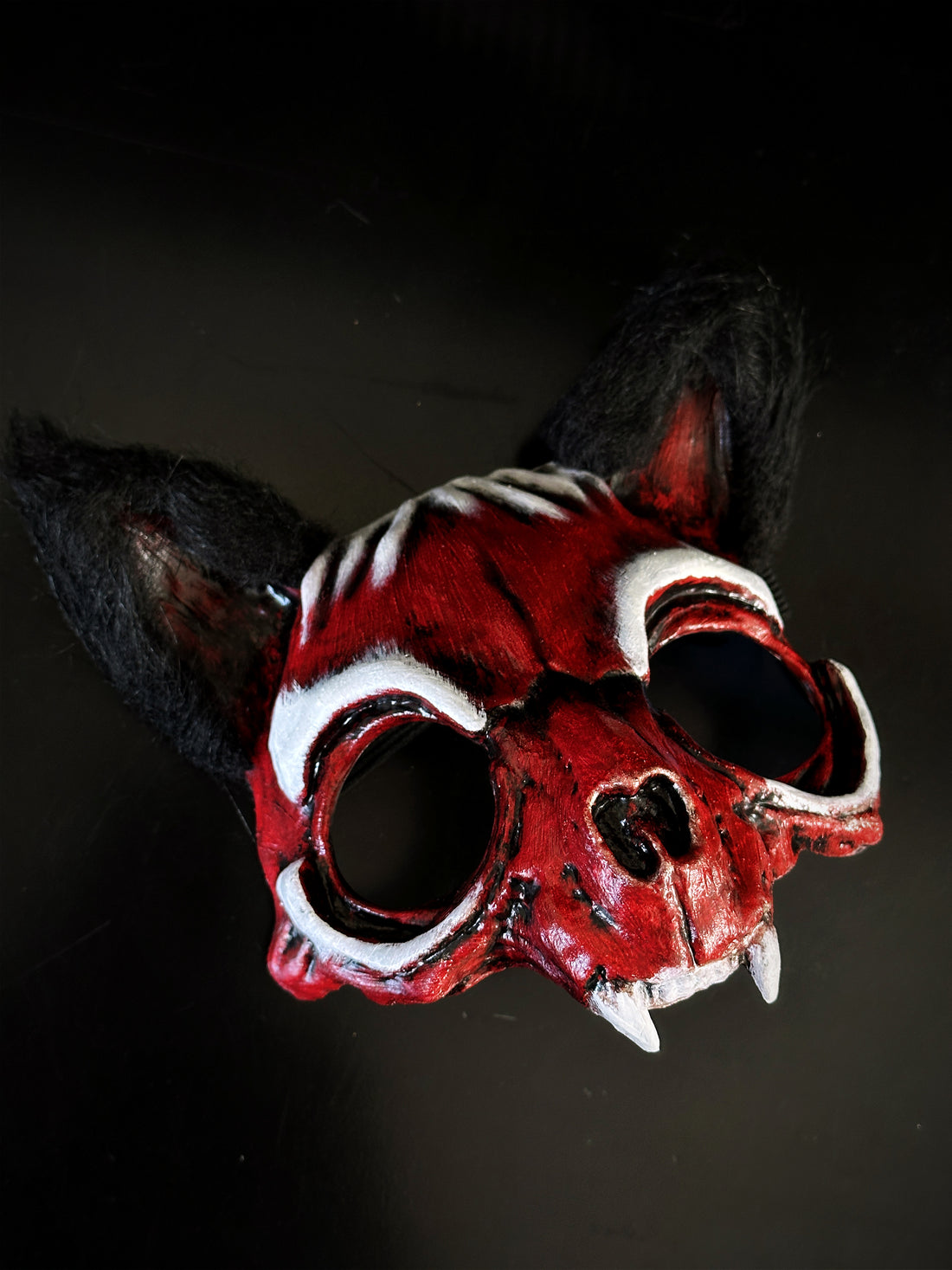 Red beast skull masquerade mask with faux fur ears, white bone stripes, and fang accents for Halloween cosplay and horror costumes.