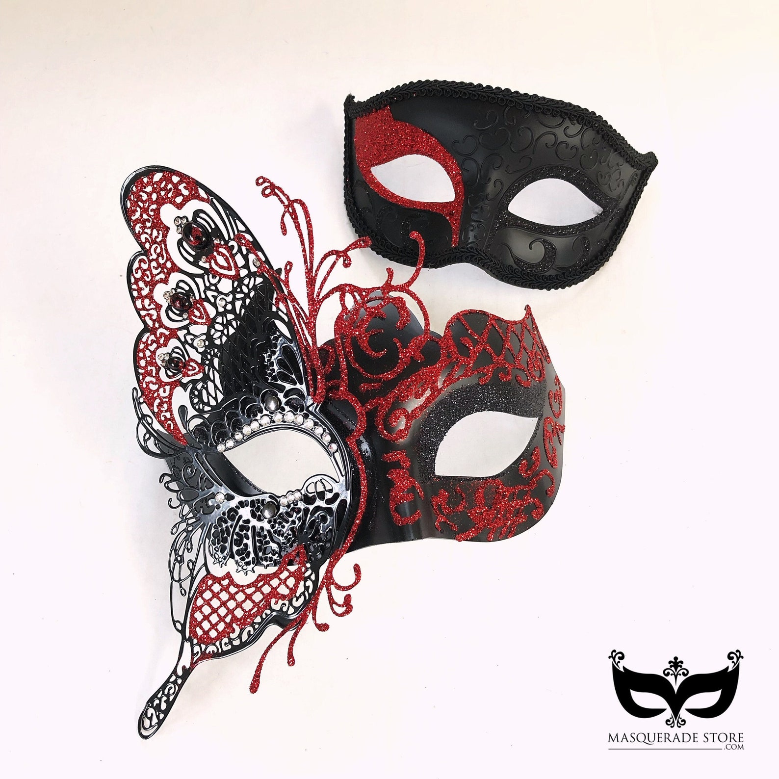 Couple’s masquerade masks featuring a women’s red and black butterfly lace rhinestone mask and a men’s black mask with bold red glitter accents.