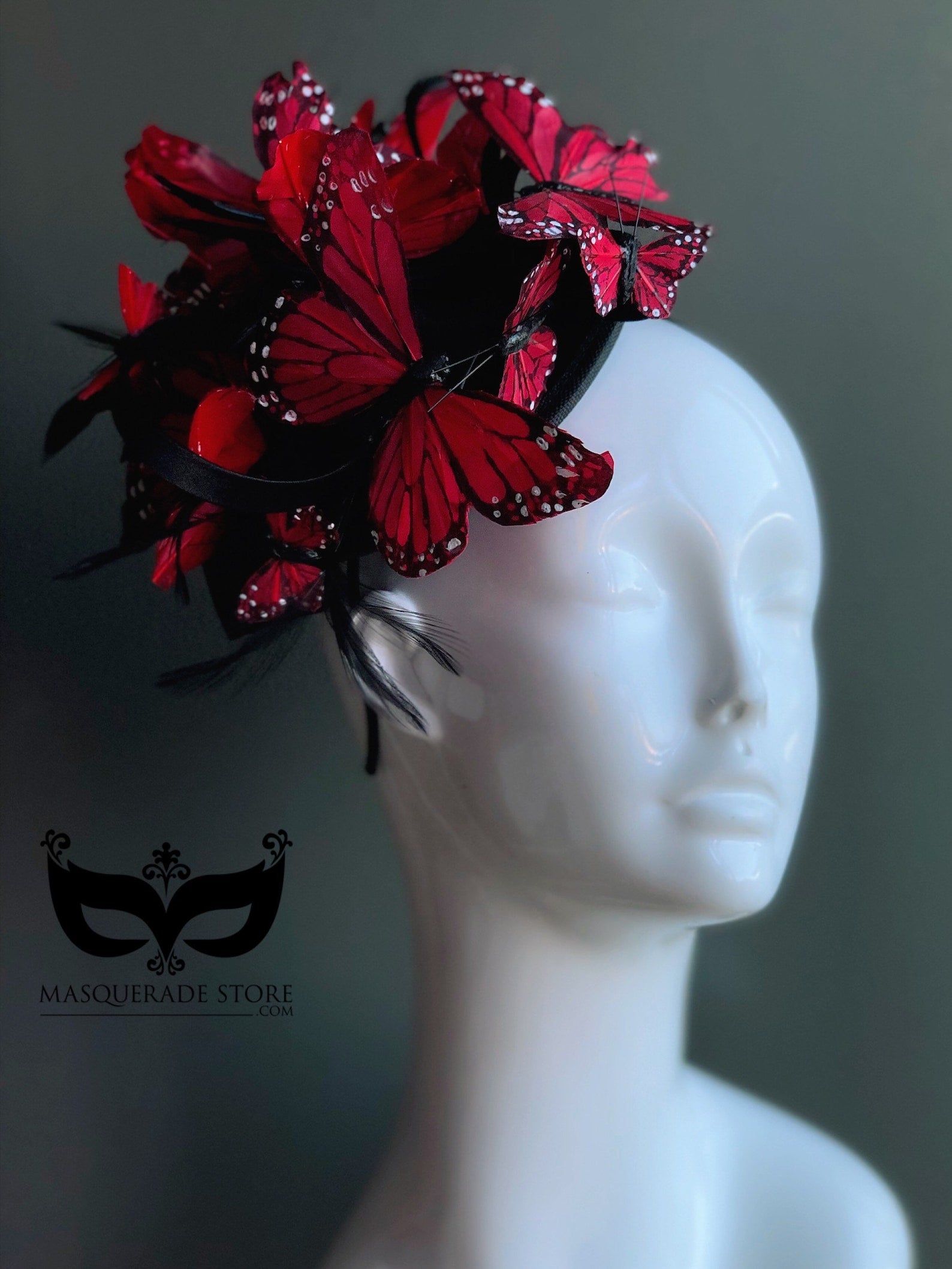 Whimsical headpiece featuring vibrant red butterflies arranged on a sculptural black fascinator
