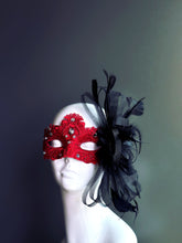 Red lace masquerade mask with rhinestones, black feathers, and tulle accents for masquerade ball, prom, or Halloween.