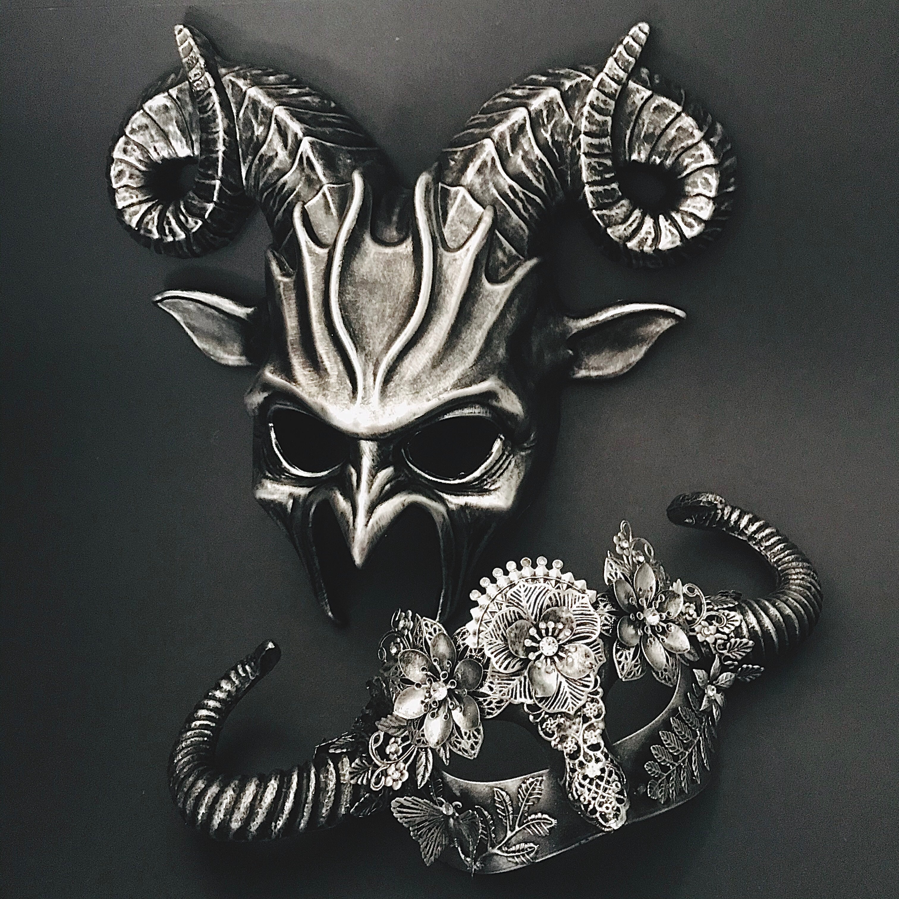 Horned silver masquerade mask duo featuring sculpted design and intricate floral lace accents.