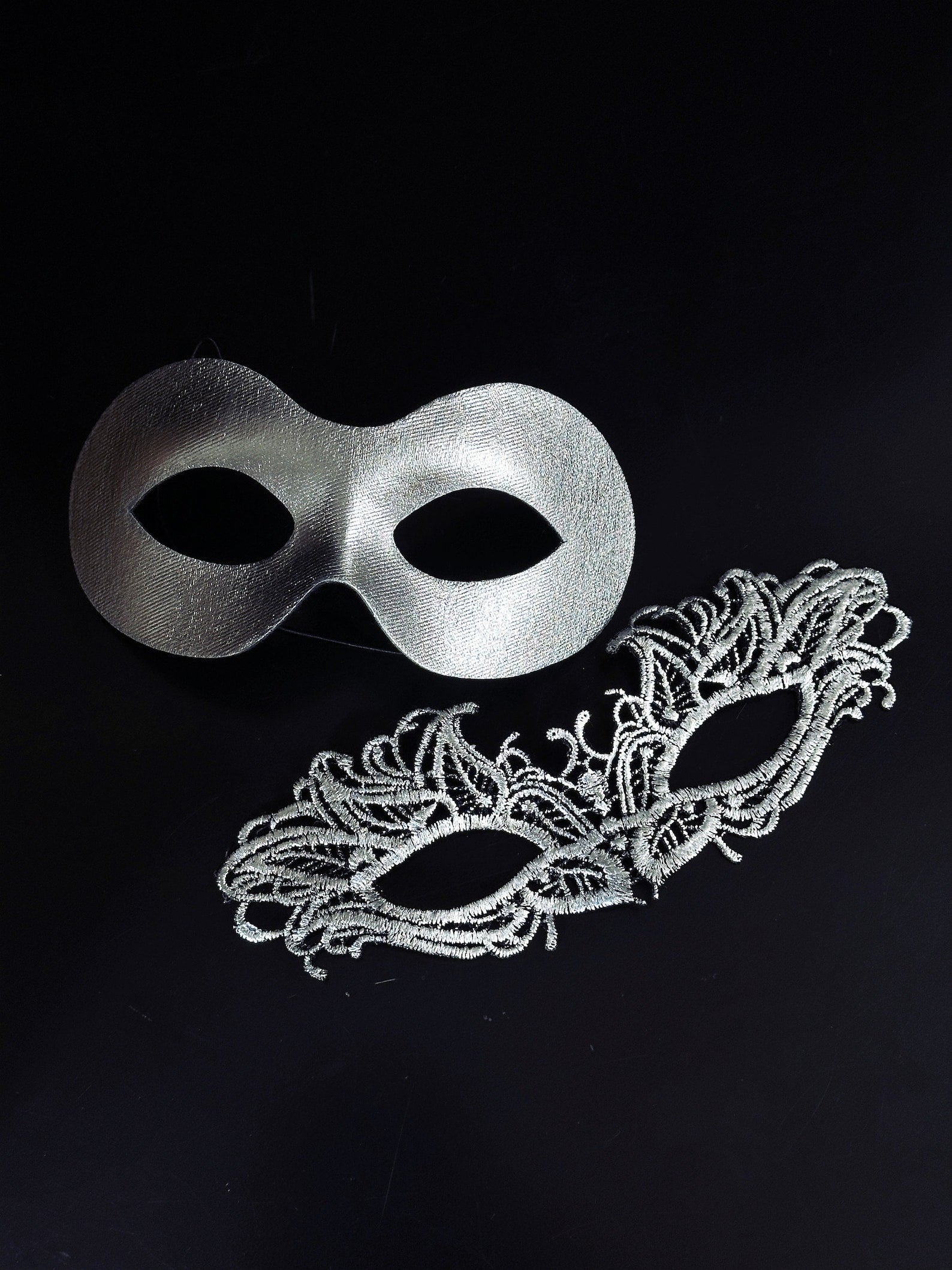 Elegant silver couples masquerade masks featuring a sleek metallic men’s mask and a delicate lace women’s mask, perfect for Venetian balls, weddings, and formal celebrations.