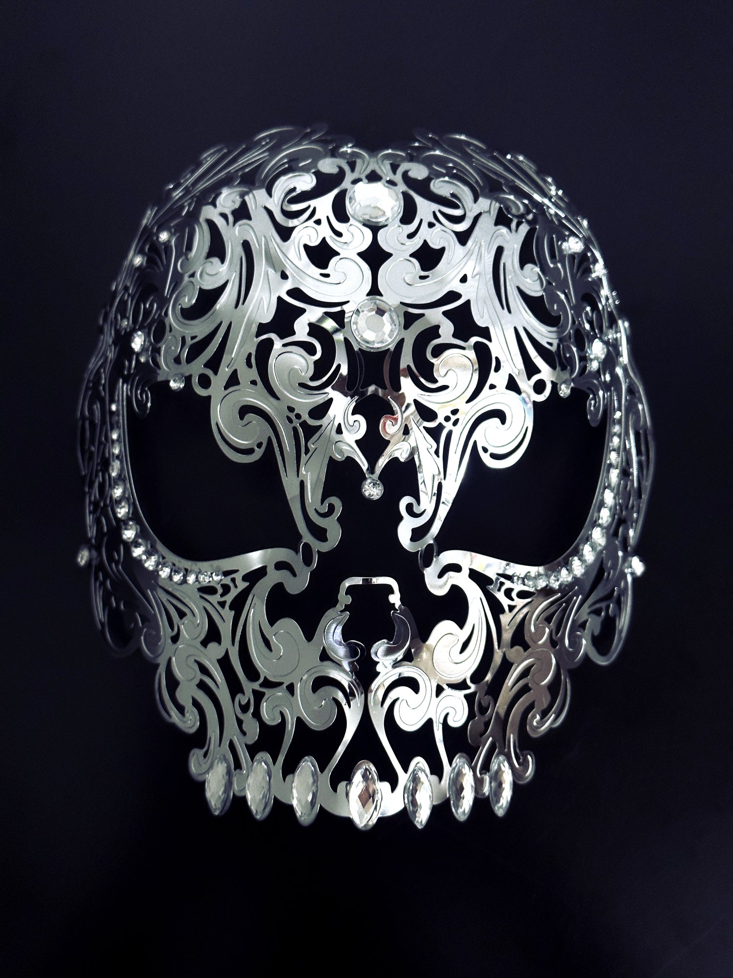 Intricate silver gothic skull face mask with cutout eyes and decorative design