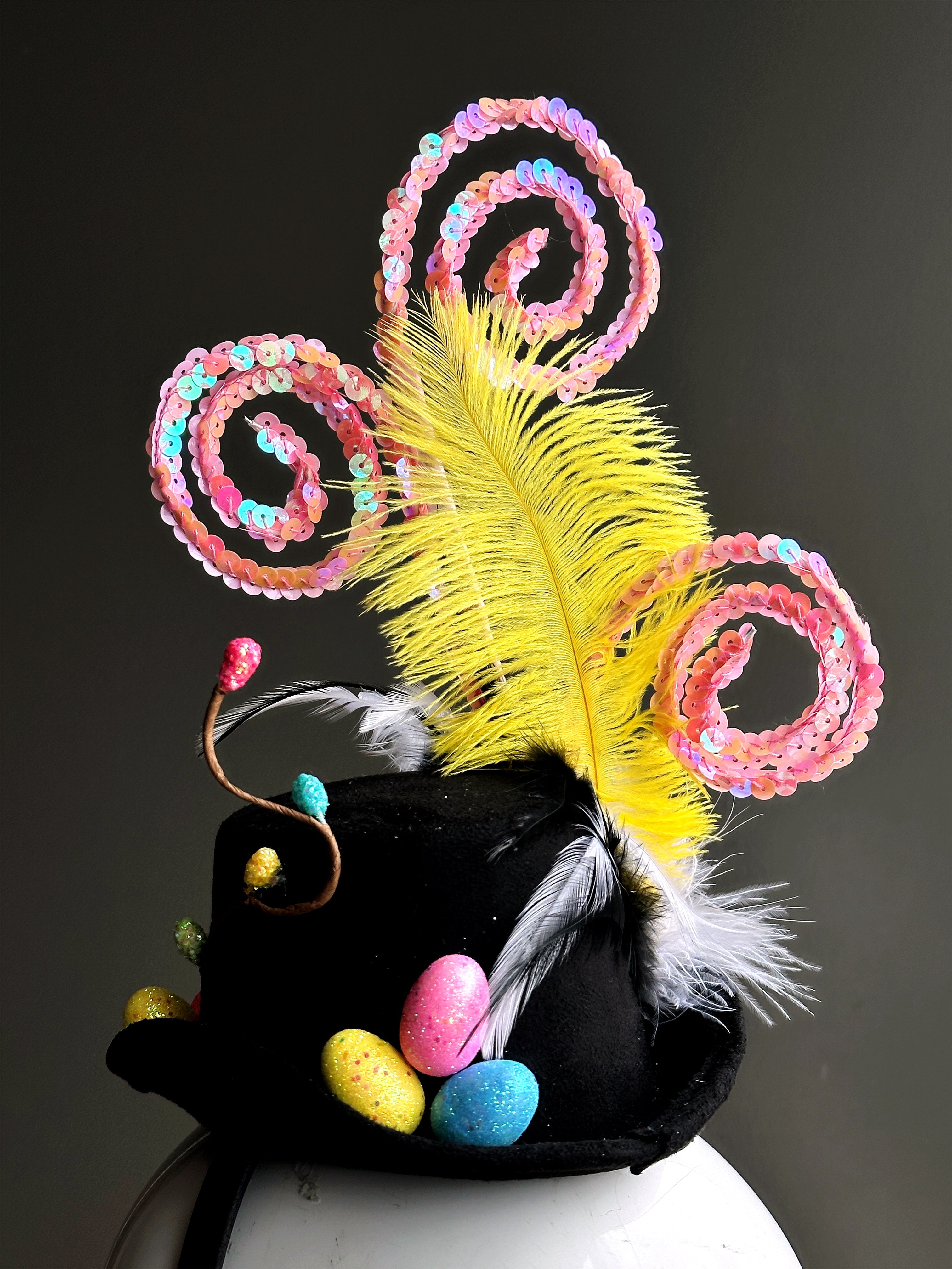 Black Easter fascinator hat decorated with colorful spring embellishments, feathers, and candy-inspired spirals