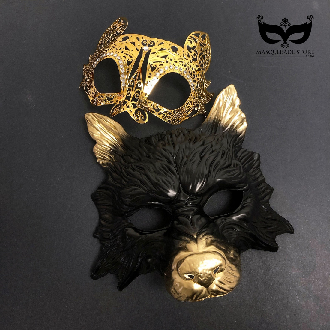 Black and gold wolf masquerade mask with metallic accents paired with a golden cat filigree rhinestone mask for couples.