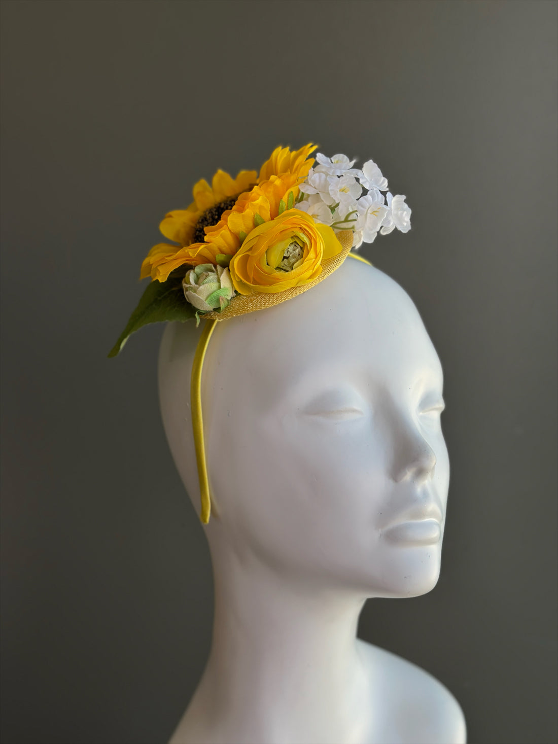 Yellow sunflower fascinator hat with ranunculus and white flowers for derby and wedding events.