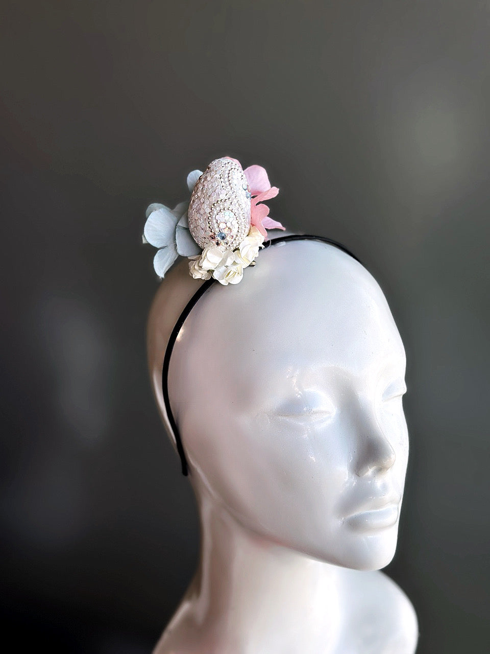 Bejeweled Easter fascinator headband with a rhinestone egg and pastel flowers, perfect for spring celebrations and festive occasions.