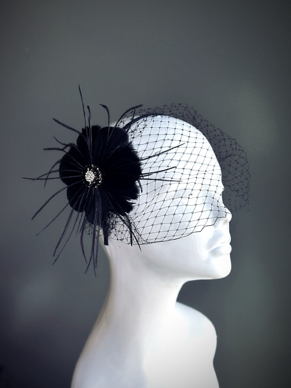 "Black feather fascinator with a rhinestone center and a delicate mesh veil, perfect for weddings and elegant events."