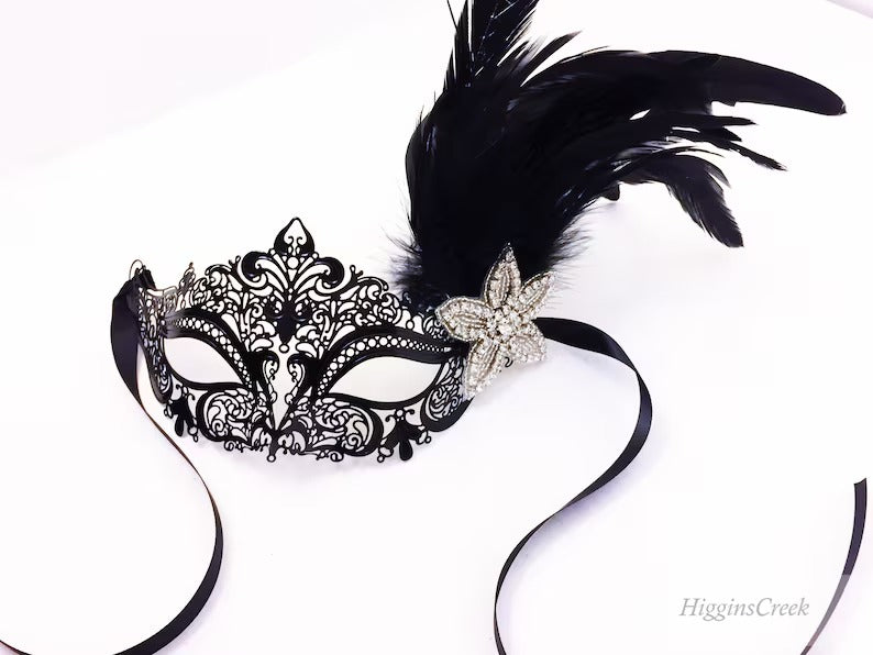 Ornate black masquerade mask with feather accents and rhinestone flower, perfect for prom, masquerade ball, or carnival event.