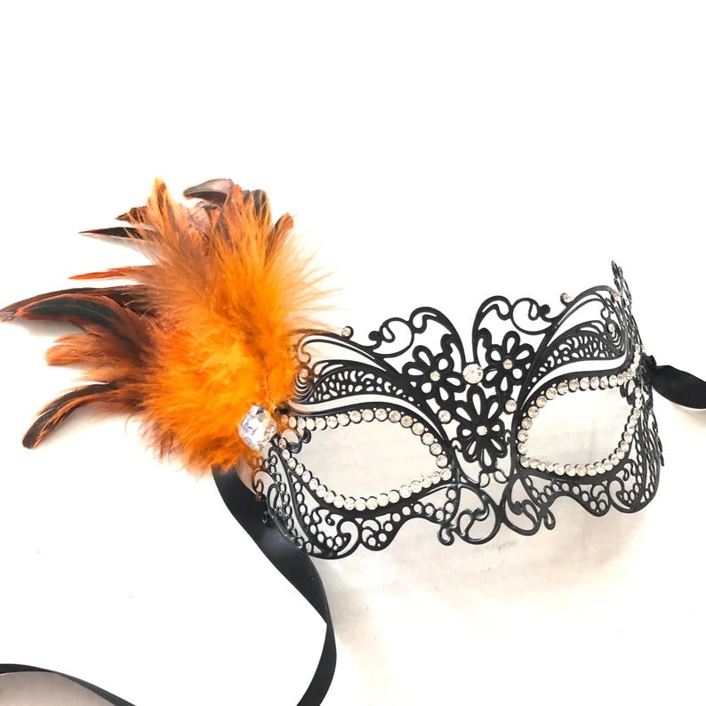 Elegant black filigree masquerade mask with bright orange feathers and rhinestone details.