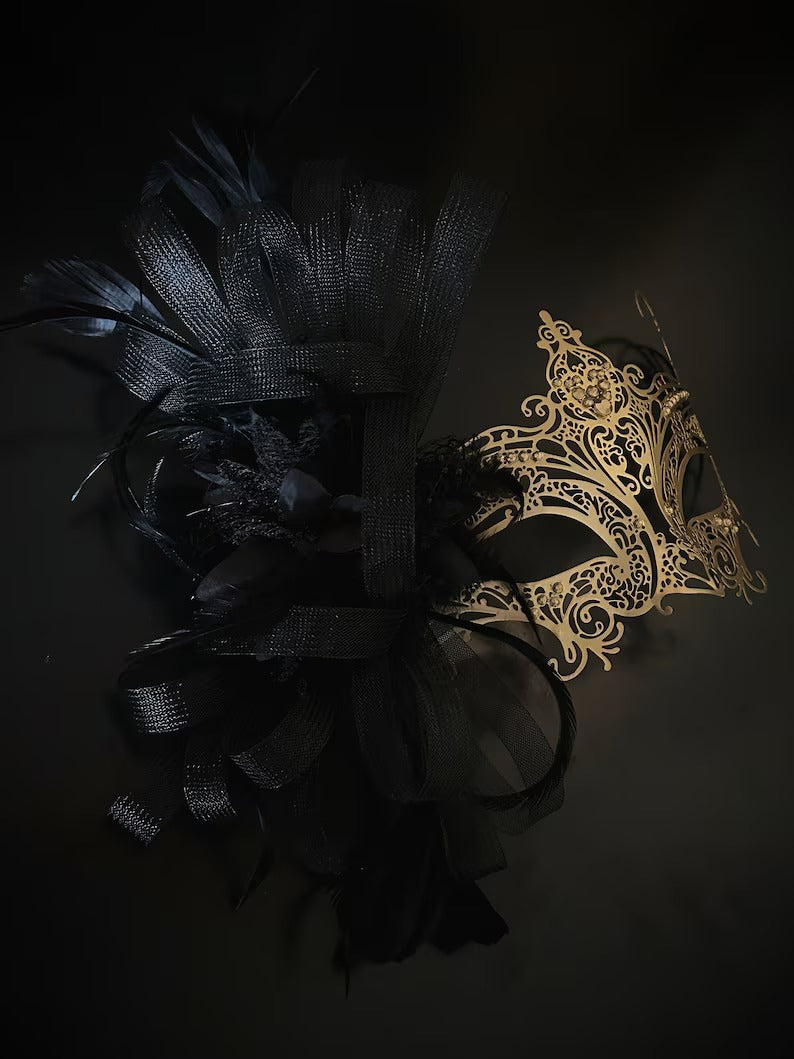 Elegant black and gold masquerade mask with feathers and filigree lace metal for women, perfect for Venetian balls and proms.