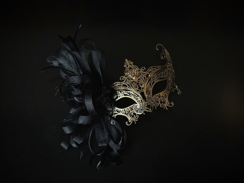 Elegant black and gold masquerade mask with feathers and filigree lace metal for women, perfect for Venetian balls and proms.