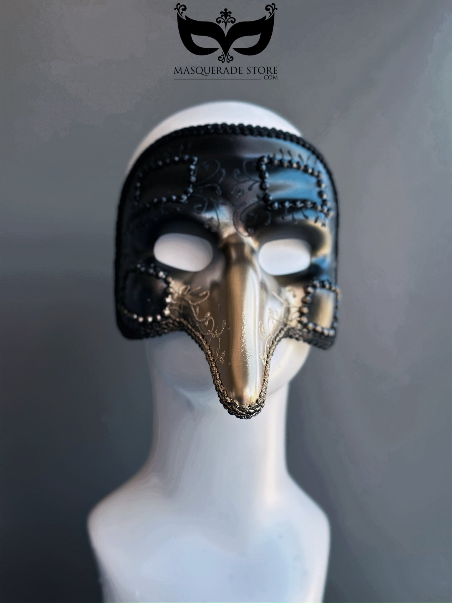 Black and gold plague doctor masquerade mask with long nose and ornate trim, inspired by Venetian Carnival traditions.