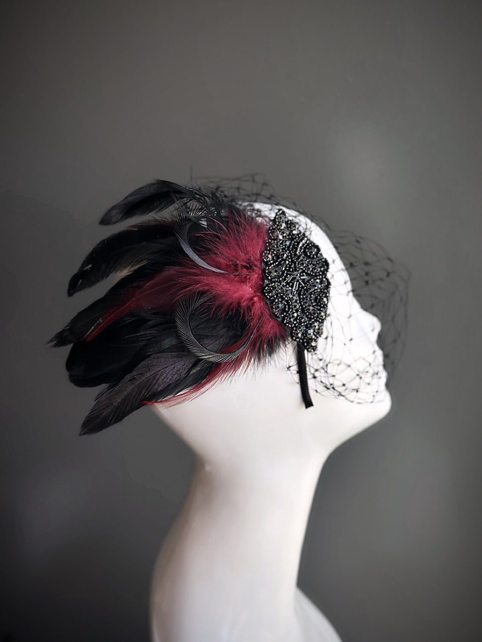 Black and red feather fascinator with beaded details and birdcage veil, perfect for Gatsby-themed parties and formal events.