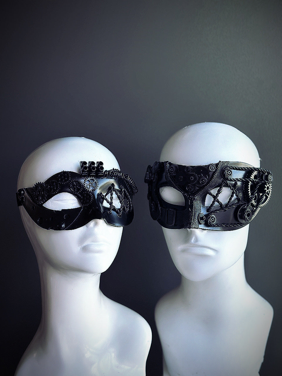 Black steampunk couples masquerade mask set with intricate gear details and industrial designs displayed on mannequin heads.