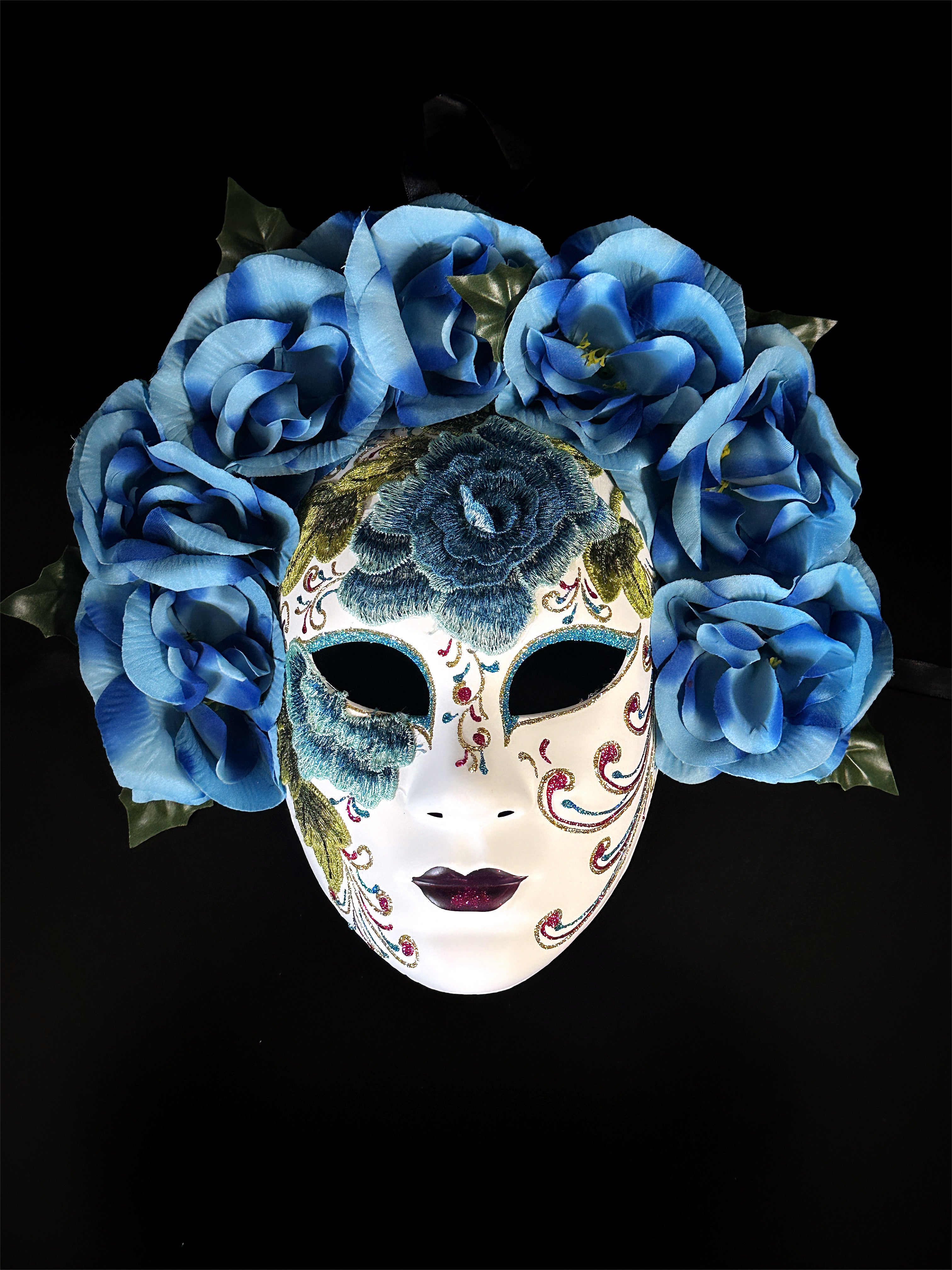 Blue floral mask with embroidered detailing, featuring blue roses and intricate designs, inspired by Venetian craftsmanship