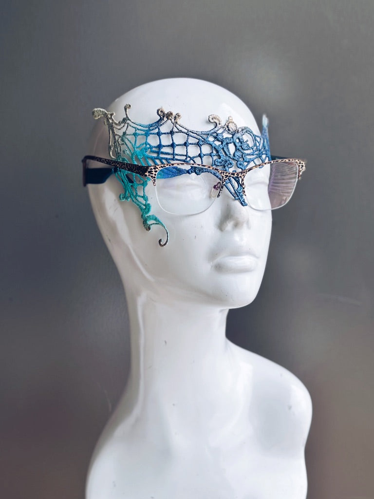 Blue, teal, and gold lace mask designed for eyeglass wearers on a white mannequin head