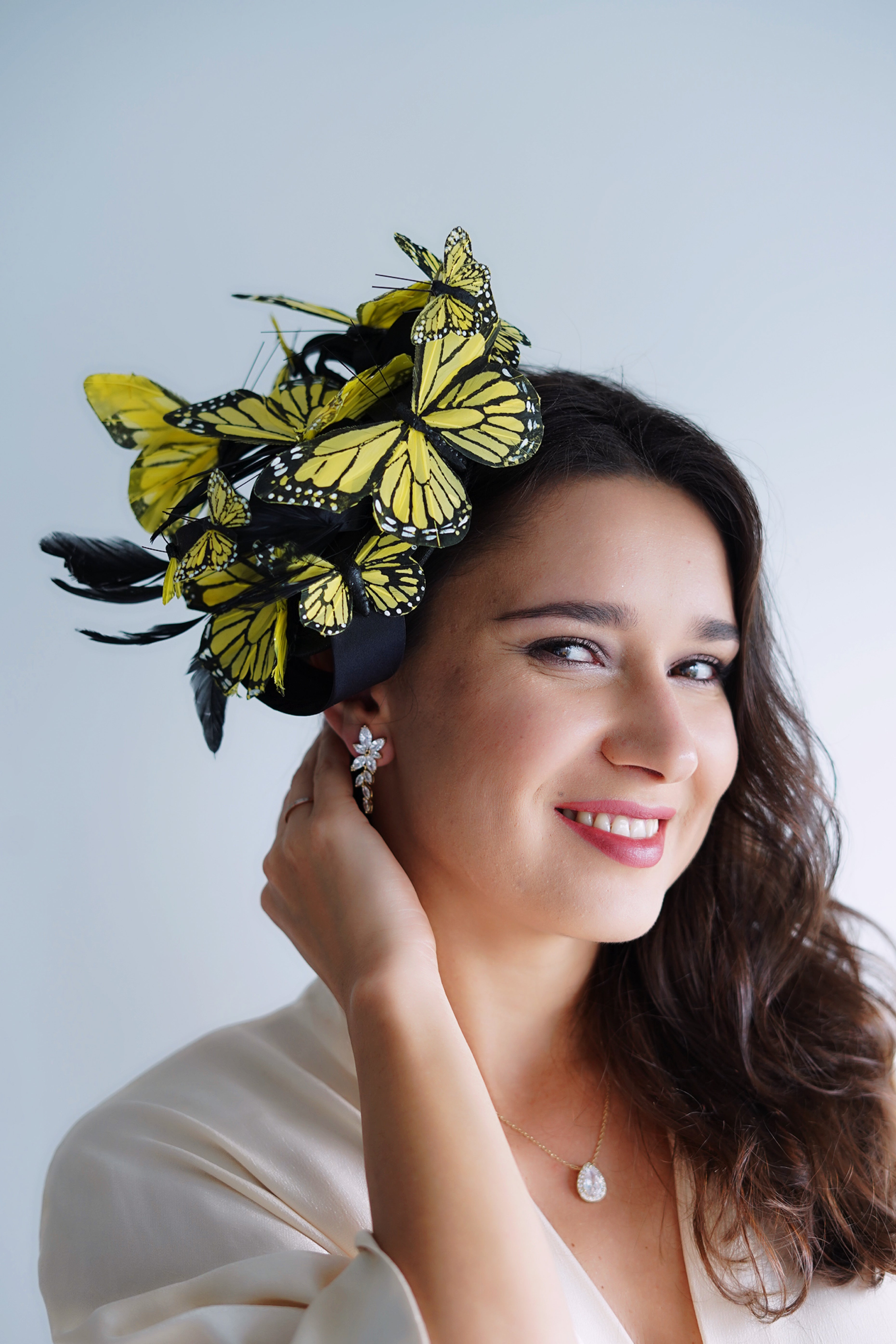 Fascinator hat on a black base with yellow black butterflies and feathers.