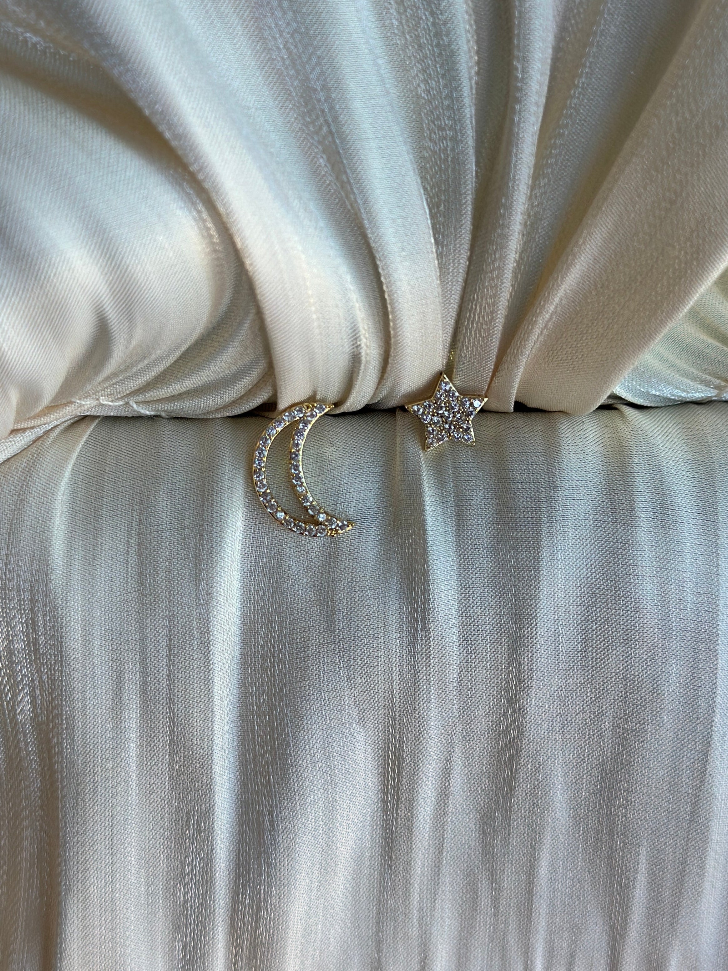 Gold moon and star earrings on ivory satin background