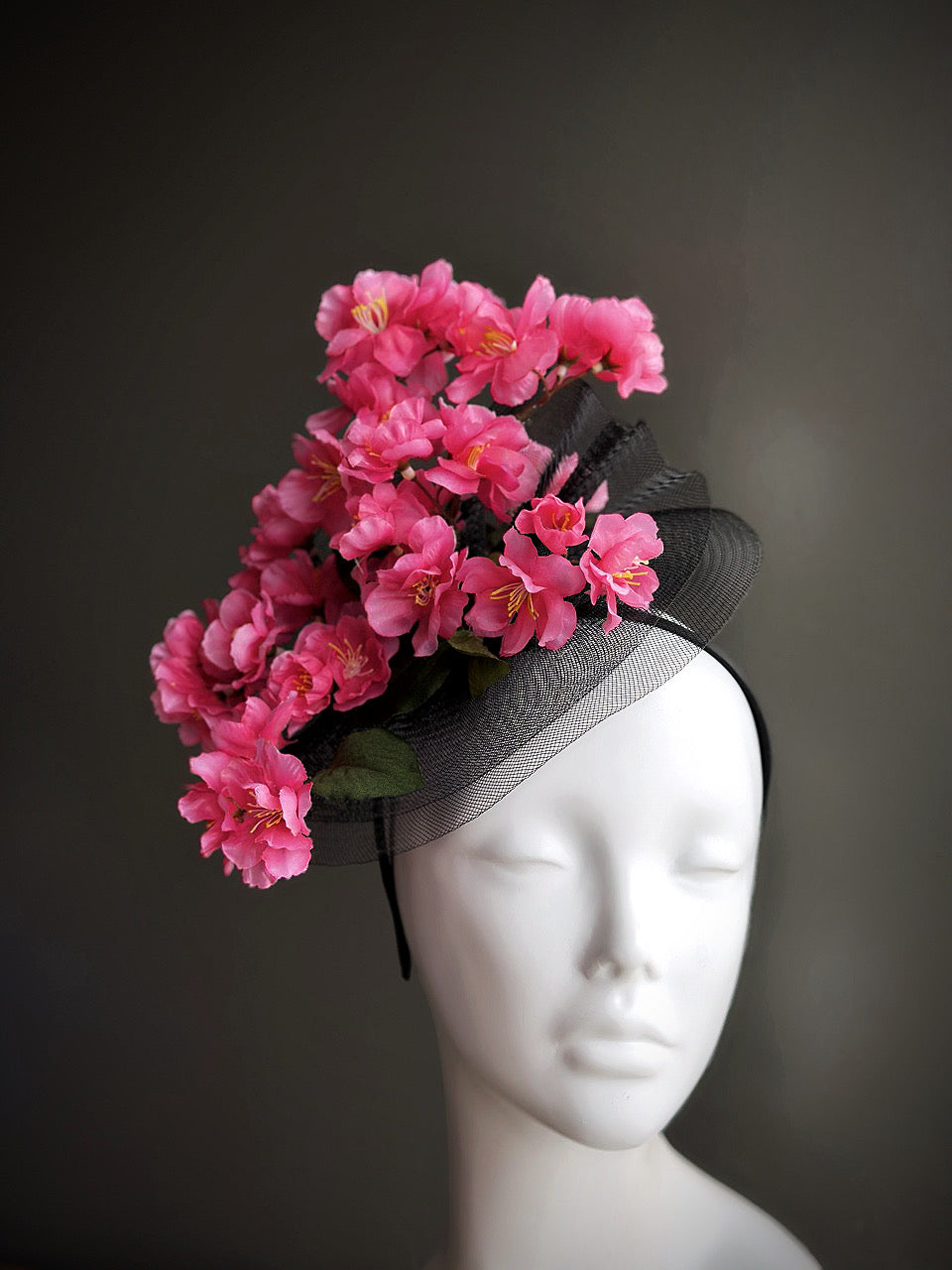 Black fascinator hat with pink cherry blossom flowers on mannequin