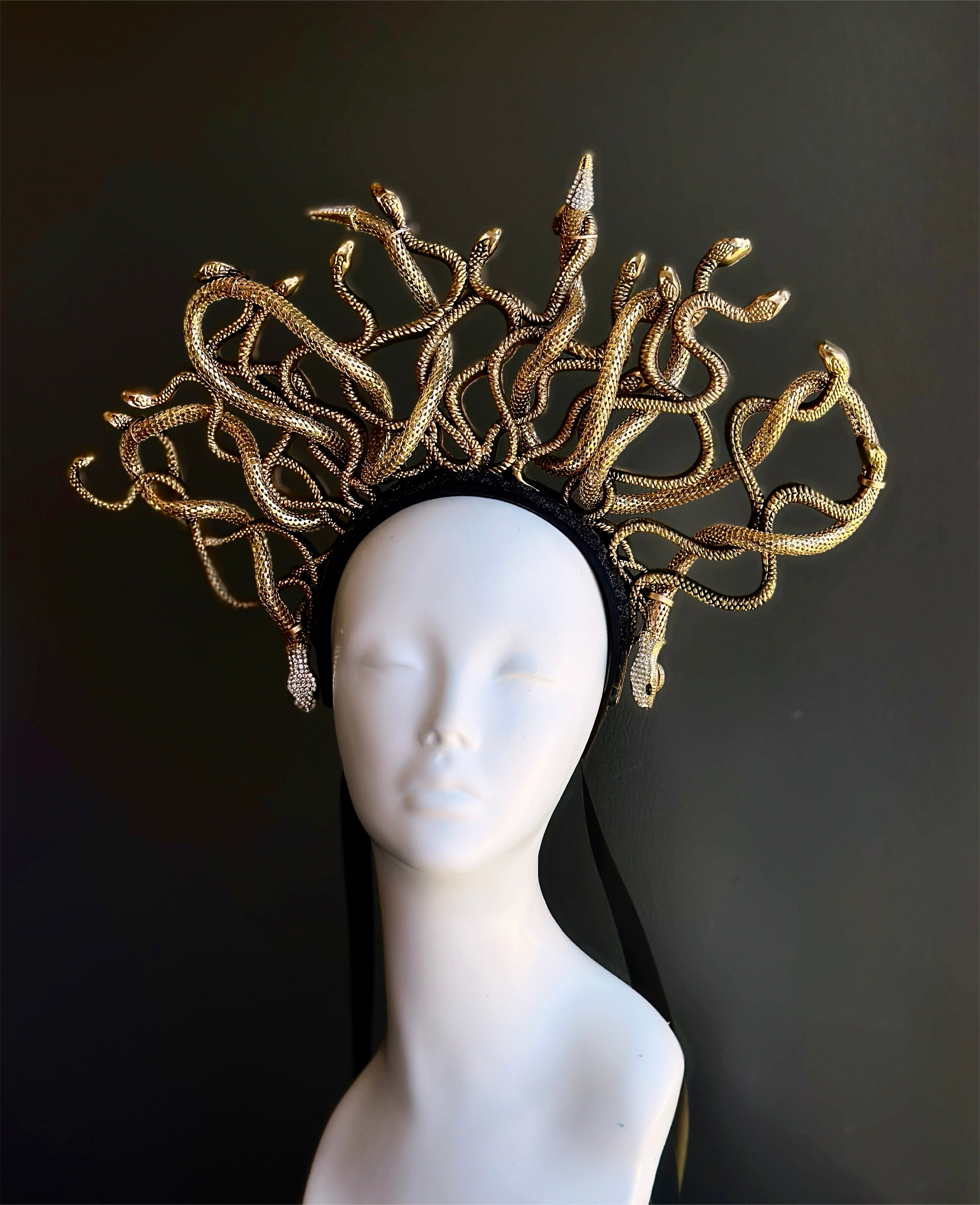 Gold snake headpiece on a mannequin head against a black background