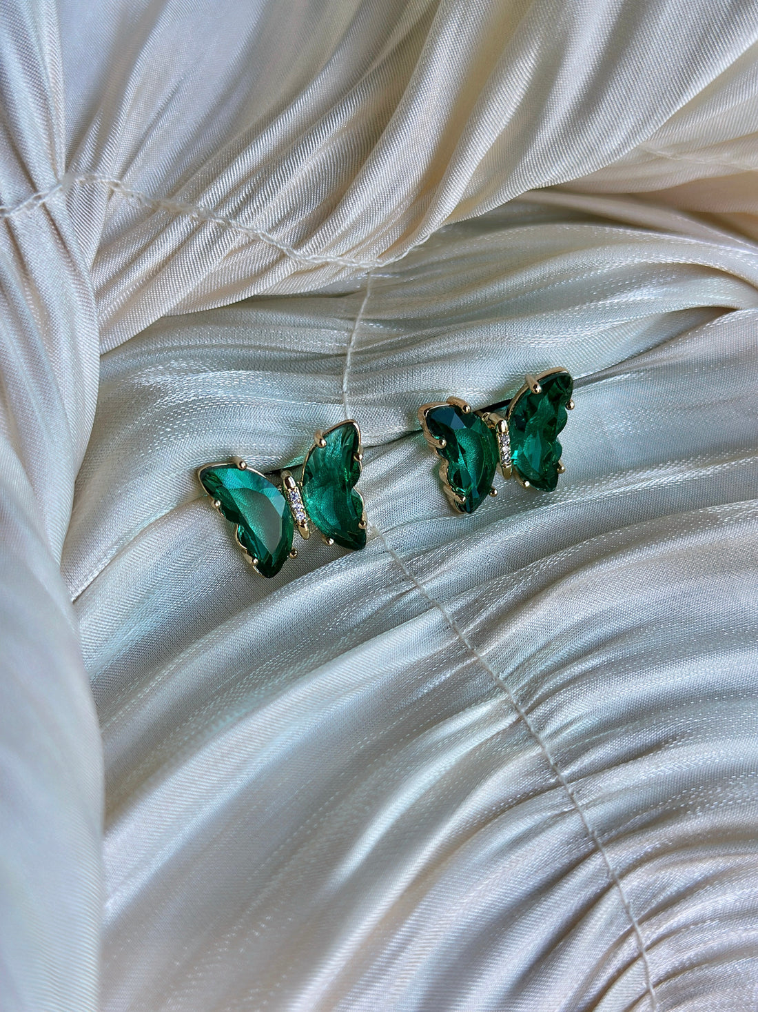 Emerald green butterfly earrings with faceted crystals and delicate accents.