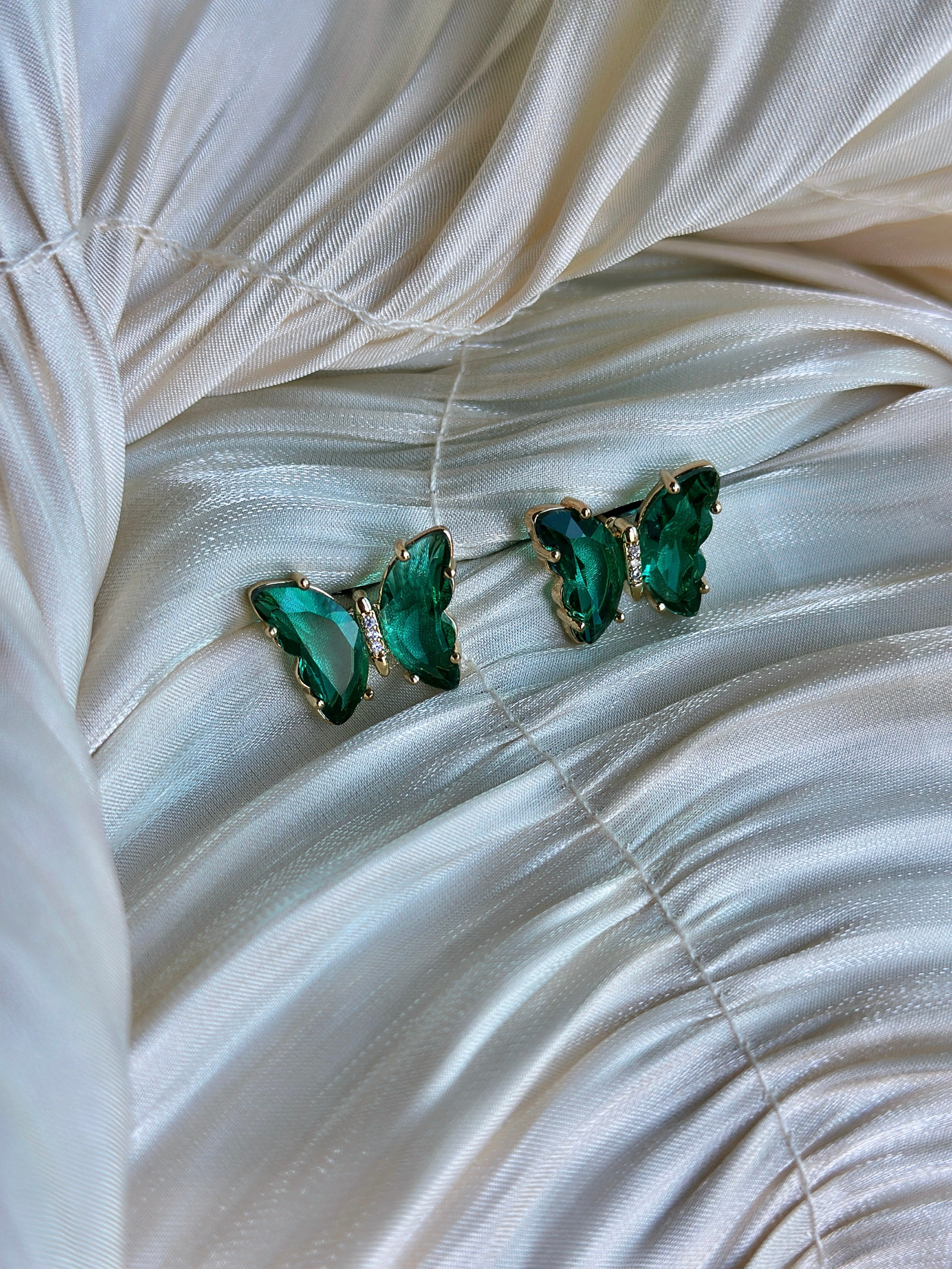 Emerald green butterfly earrings with faceted crystals and delicate accents.
