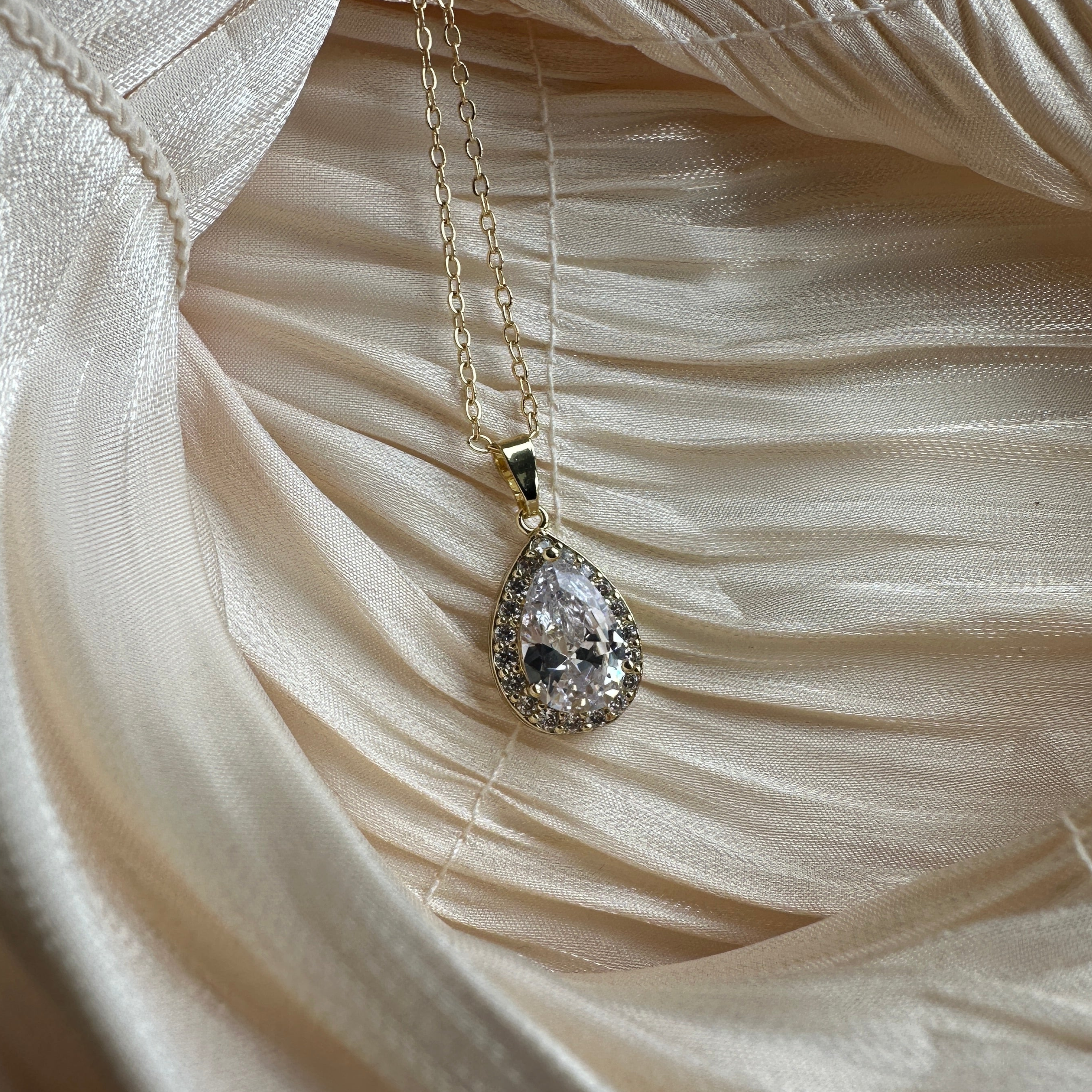 Gold necklace with a teardrop-cut crystal encased in a shimmering halo.