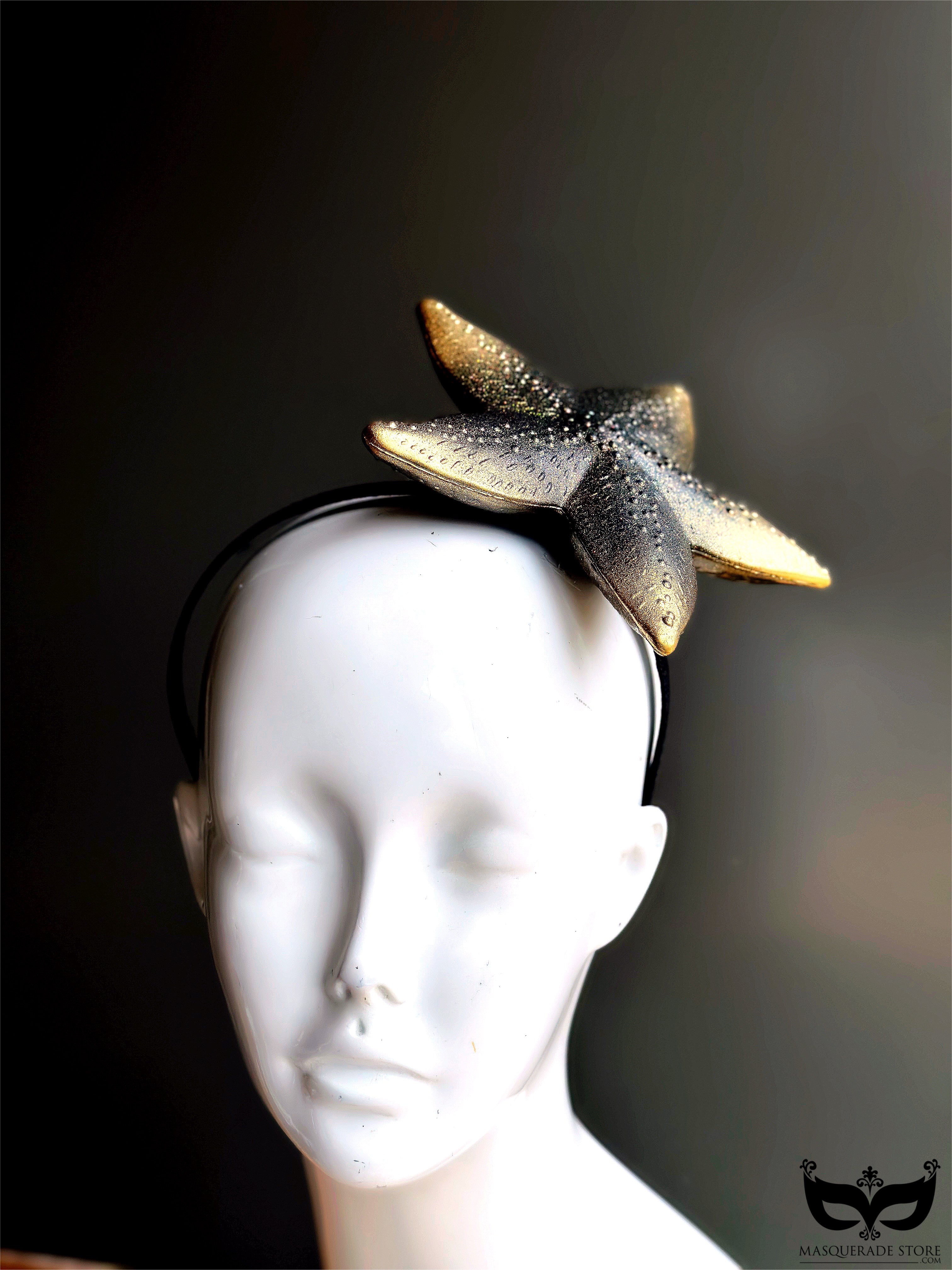 A gold and black starfish fascinator mounted on a headband, ideal for beach-themed events, mermaid looks, and bold statement fashion.