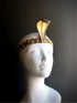 Gold cobra headpiece with intricate detailing, inspired by Ancient Egyptian serpent designs, displayed on a white mannequin