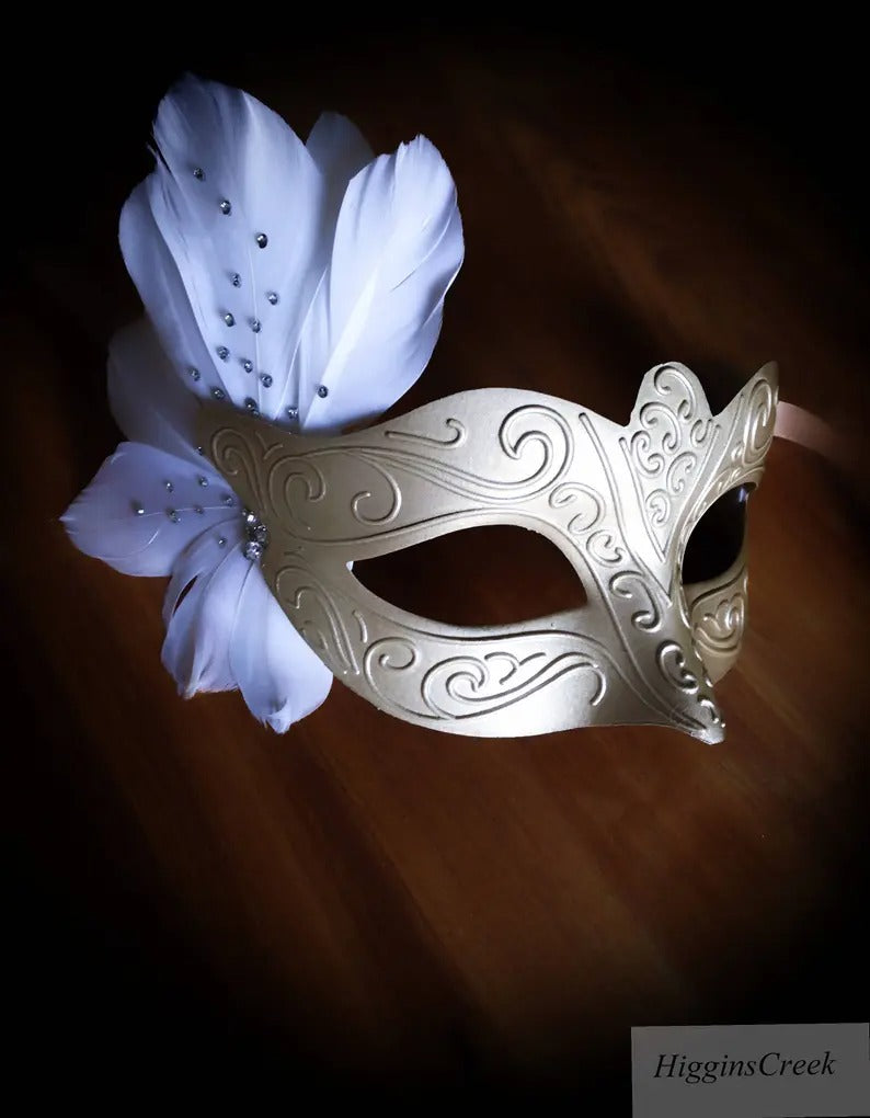 Elegant gold mask with white feathers and rhinestones for masquerade balls, proms, and weddings.