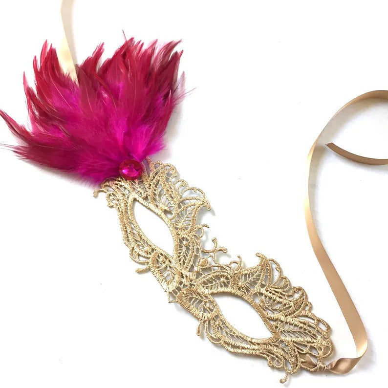 Elegant gold lace mask with pink feathers and jewel accent, perfect for weddings, proms, and masquerade balls.